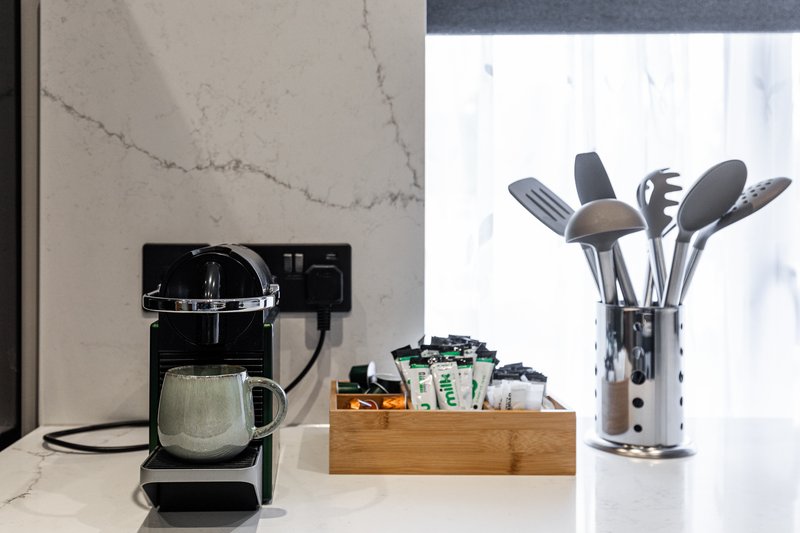 Kitchen counter with coffee maker, wooden utensil holder, and cooking utensils near window