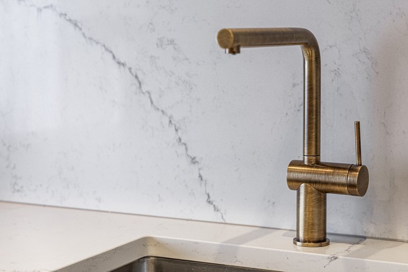 Modern kitchen sink with brass tap and marble splashback wall