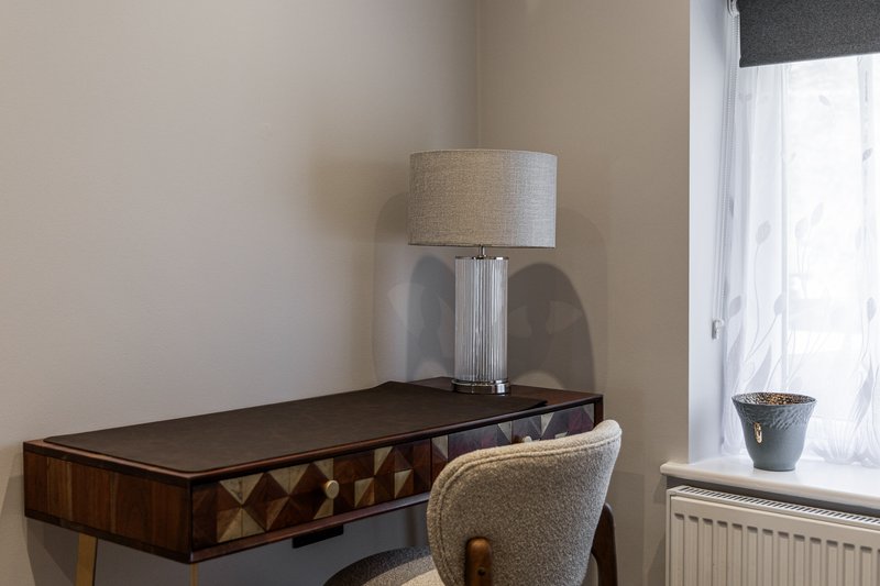 Desk with lamp, chair and potted plant beside bright window