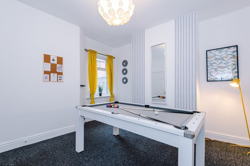 Modern recreation room with white pool table, pendant light, yellow curtains and wall art