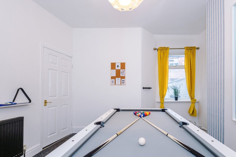 Games room with pool table, yellow curtains, and window with radiator