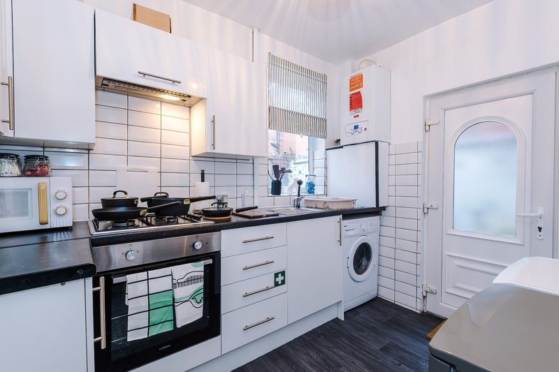 Modern kitchen with white units, gas hob, integrated washing machine and tiled splashback