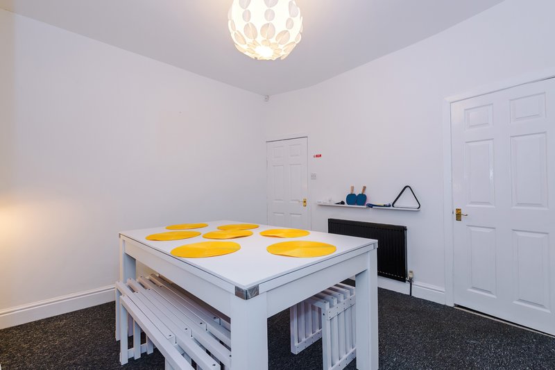 Bright room with white ceiling light, yellow table with storage, white doors and dark carpet flooring