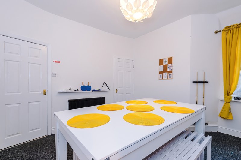 Bright studio space with white table, yellow plates, pendant light, and yellow curtains