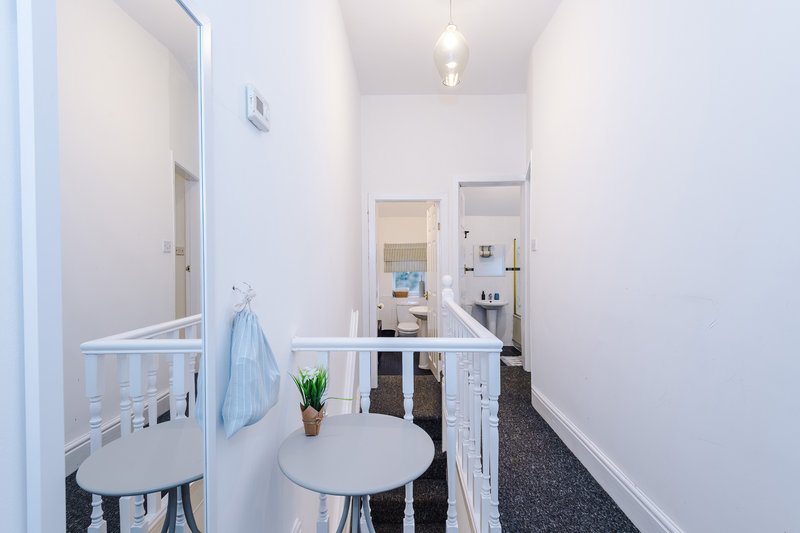 Bright hallway with white walls, small round table, chair, and hanging towel