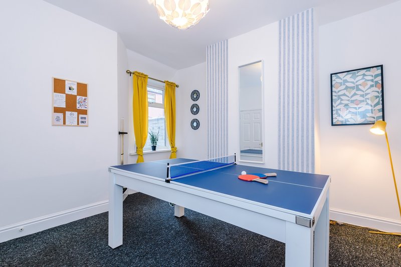 Games room with ping pong table, yellow curtains, white walls and modern lighting
