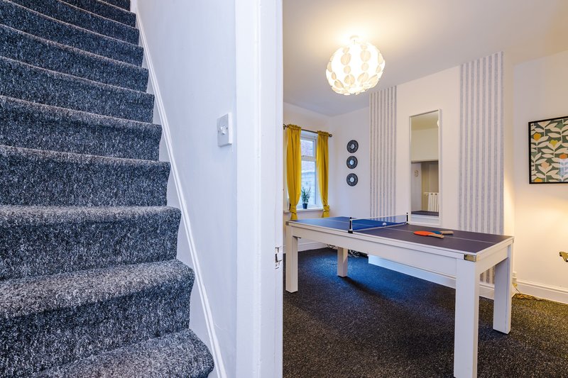 Open-plan hallway with staircase, games room with pool table and ping-pong setup