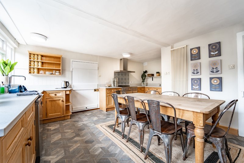 Open-plan kitchen and dining area with wooden cabinets, dining table, and wall art