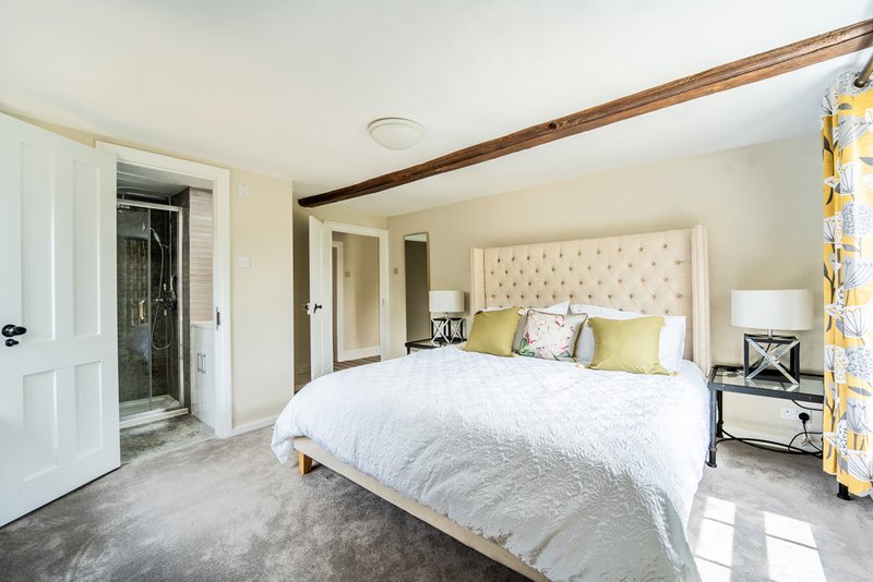 Bright bedroom with queen bed, upholstered headboard, ensuite bathroom and yellow curtains