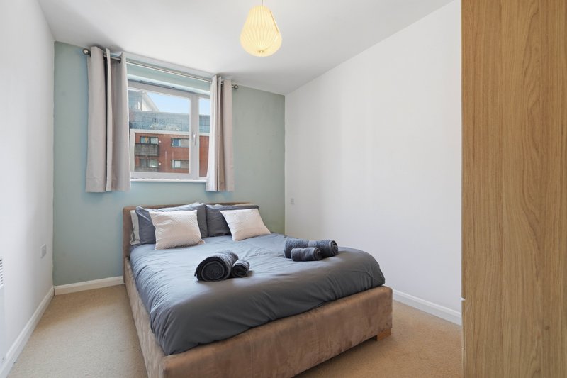 Compact bedroom with double bed, pendant light, window with curtains and city view
