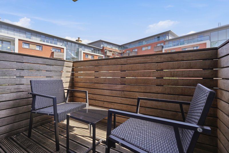 Rooftop terrace with wooden fence, two chairs, table and city views
