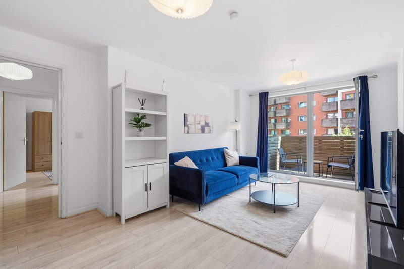 Modern living room with blue sofa, white storage unit, wooden flooring and large windows