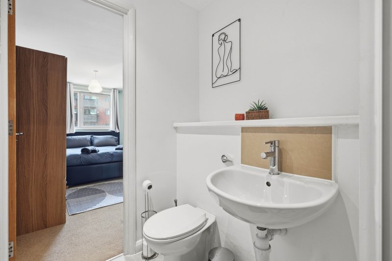 Modern bathroom with white wall-mounted sink, toilet, and minimalist line art decor