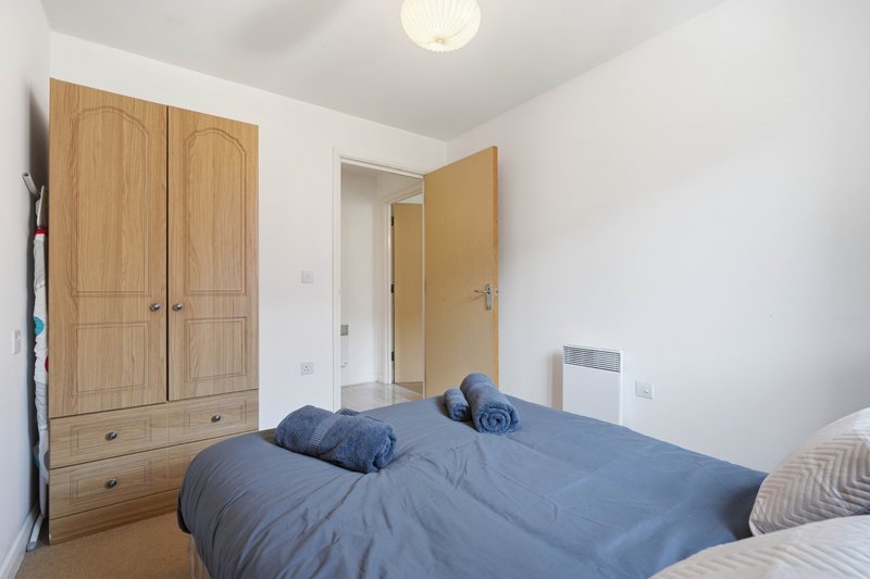 Bedroom with double bed, wooden wardrobe, and cream ceiling light fixture