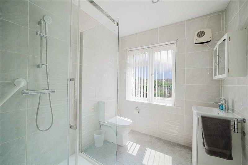 Modern bathroom with walk-in shower, toilet, sink and window with vertical blinds