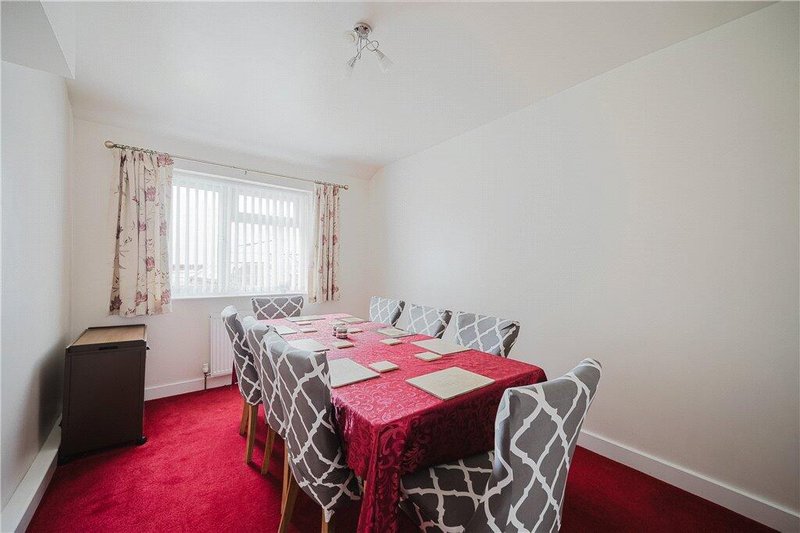 Bright dining room with red carpet, patterned chairs, and floral curtains
