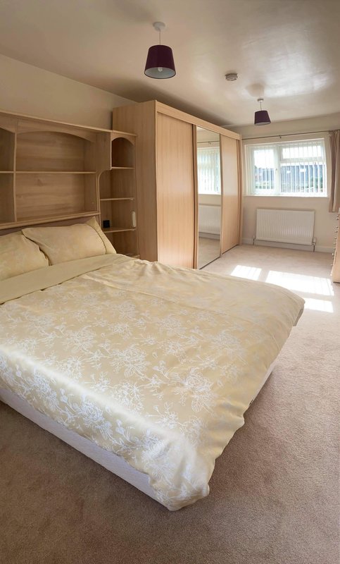 Main bedroom with double bed, built-in wooden wardrobes and shelving, pendant lights