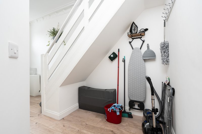 Sloped attic storage area with white walls, wooden floor, and organised sports equipment