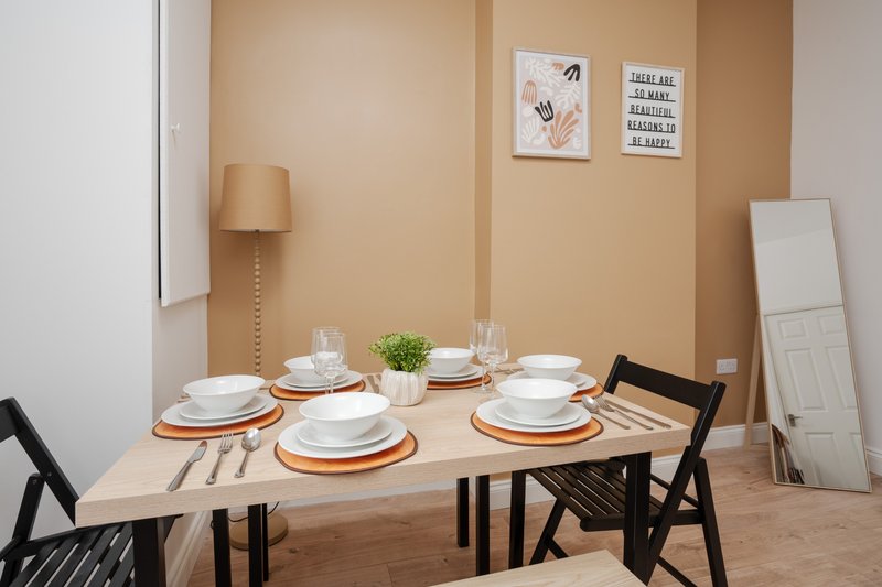 Dining room with wooden table set for four, black chairs, and neutral beige walls