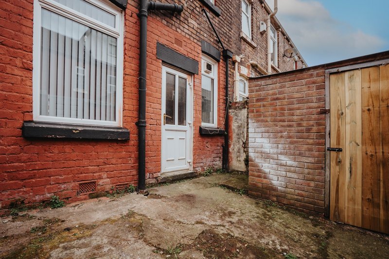 Brick terrace building exterior with white door, window, and wooden gate