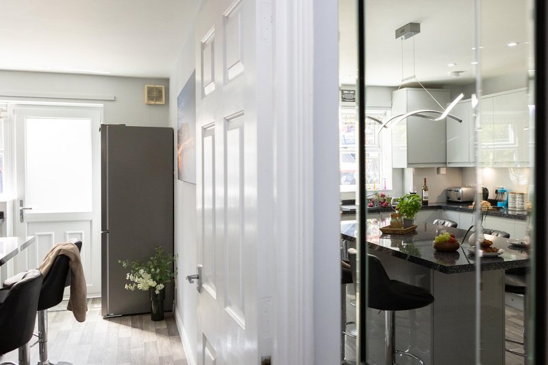 Modern galley kitchen with dark cabinetry, stainless steel appliances, and bar seating