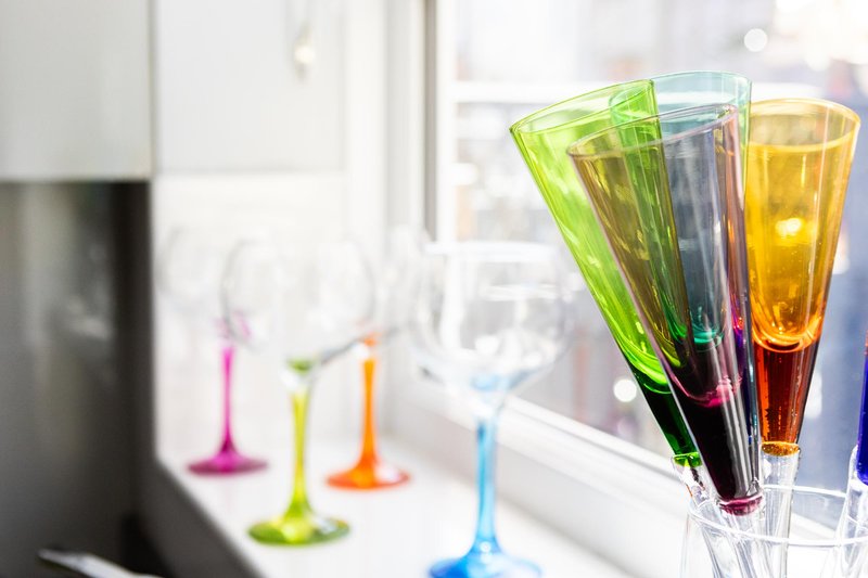Colorful glasses with liquids on windowsill, bright natural light from window