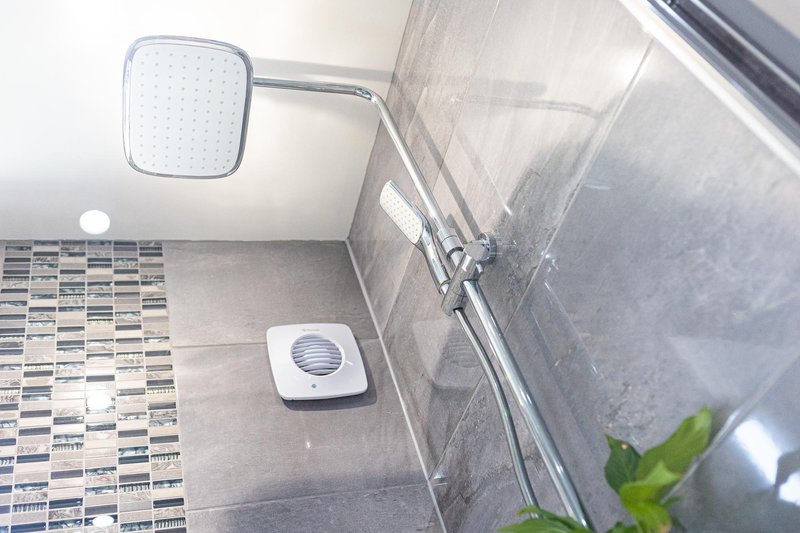 Modern bathroom with tiled floor, glass shower enclosure, overhead rain showerhead and wall-mounted fixtures