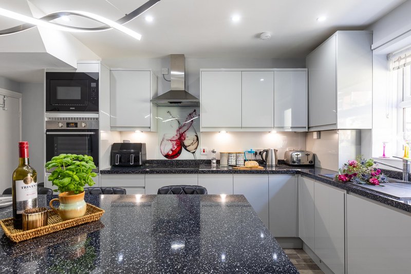 Modern kitchen with white cabinetry, dark granite countertop, stainless steel appliances and red bicycle wall decoration