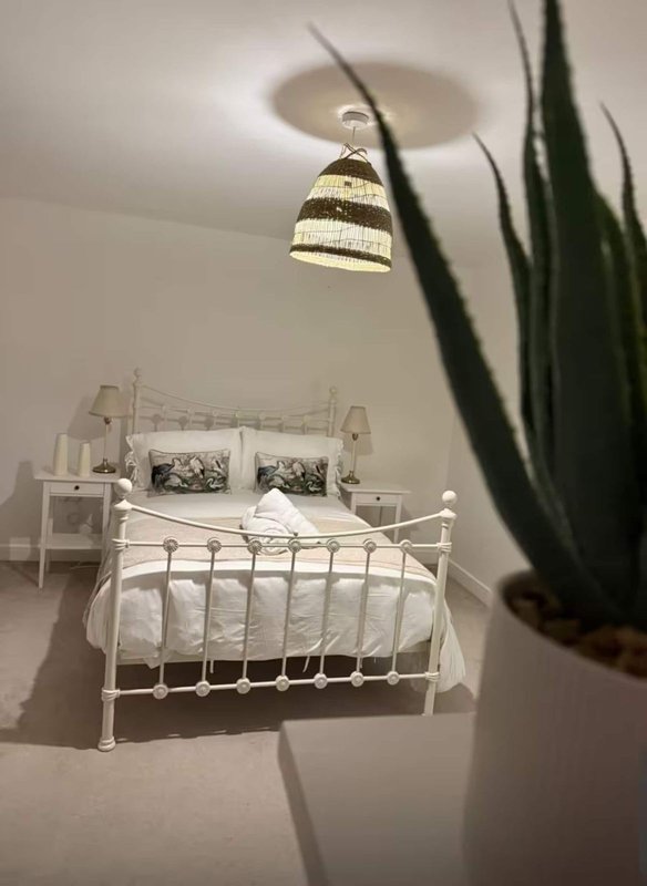 Bedroom with white metal bed frame, striped pendant lamp, potted plant and bedside tables