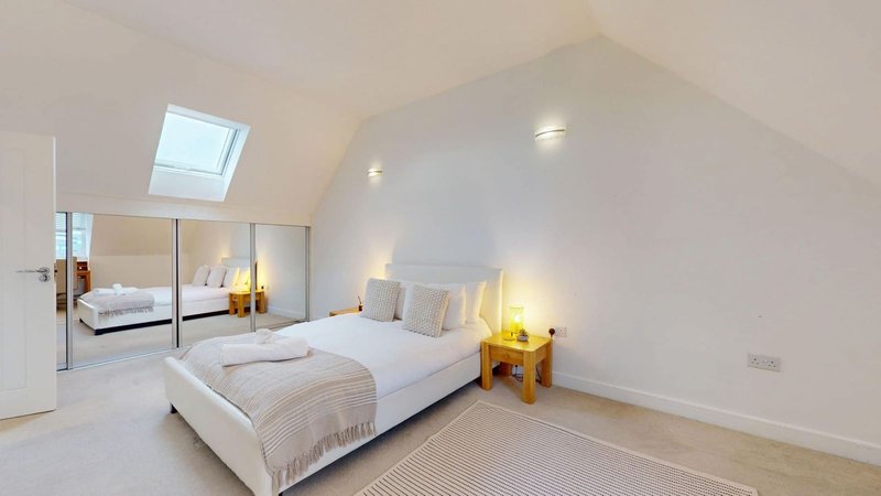 Modern bedroom with double bed, mirrored wardrobe, skylights and warm lighting