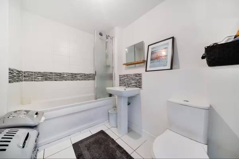 Modern bathroom with bathtub, glass shower enclosure, white toilet, and pedestal sink