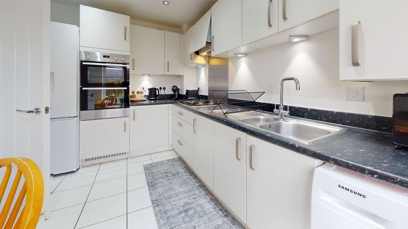 Modern kitchen with white cabinetry, black countertops, stainless steel appliances and pendant lighting