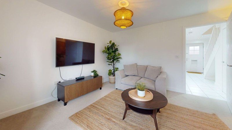 Bright living room with grey sofa, wall-mounted TV, wooden media unit and round coffee table