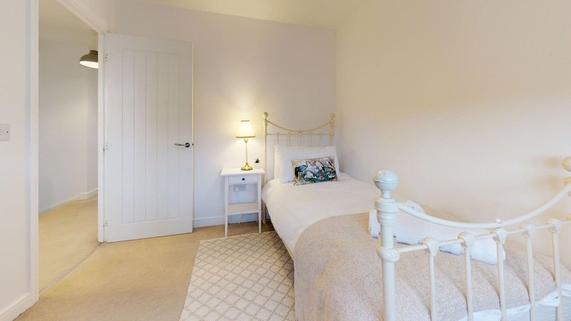 Bright bedroom with single bed, bedside table, white wardrobe and wooden flooring