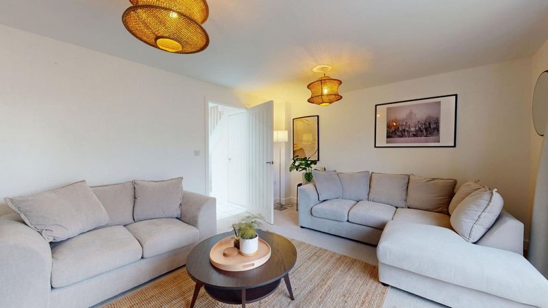 Modern living room with light grey sofas, round coffee table, and gold ceiling lights