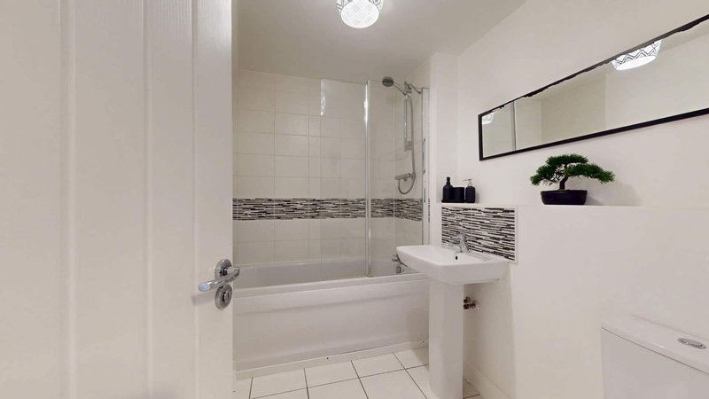 Modern bathroom with white tile, bathtub, glass shower enclosure and mirror