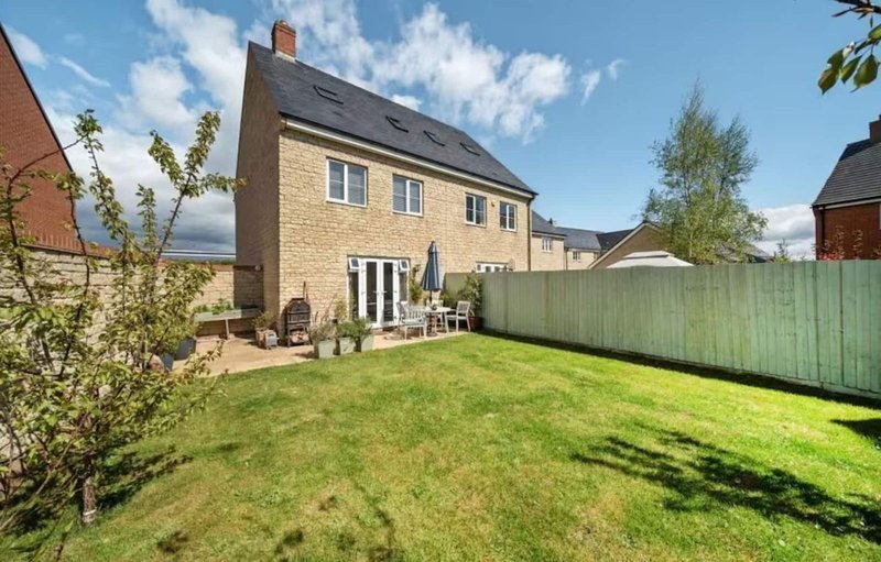 Stone detached house with garden, patio furniture and fenced lawn