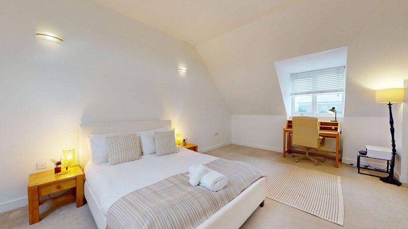 Bright attic bedroom with double bed, wooden bedside tables, desk and window