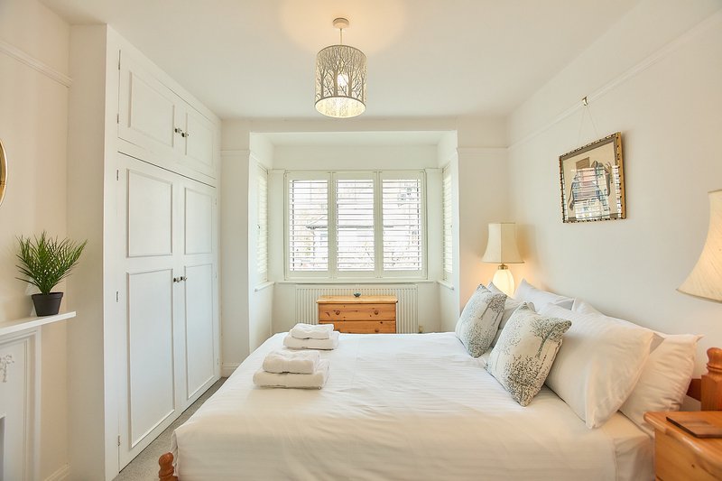 Bright bedroom with double bed, white wardrobe, shuttered window and warm lighting