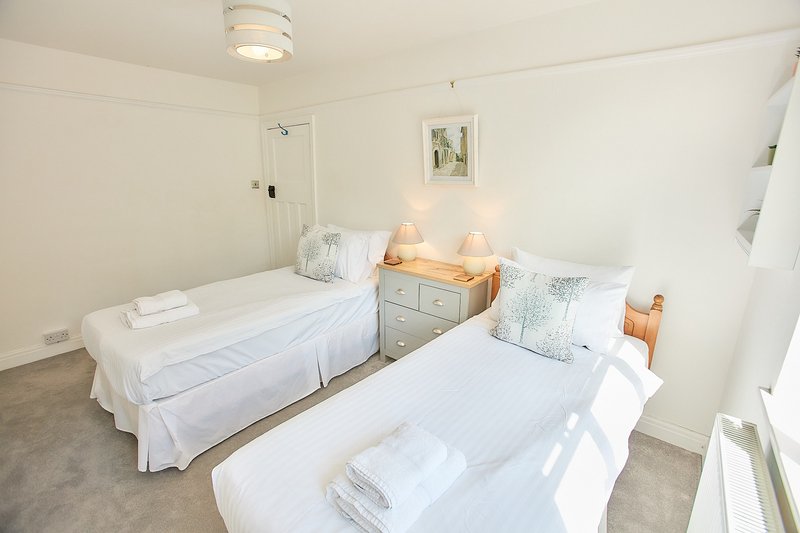Twin bedroom with two single beds, wooden bedside tables, lamps and ensuite bathroom