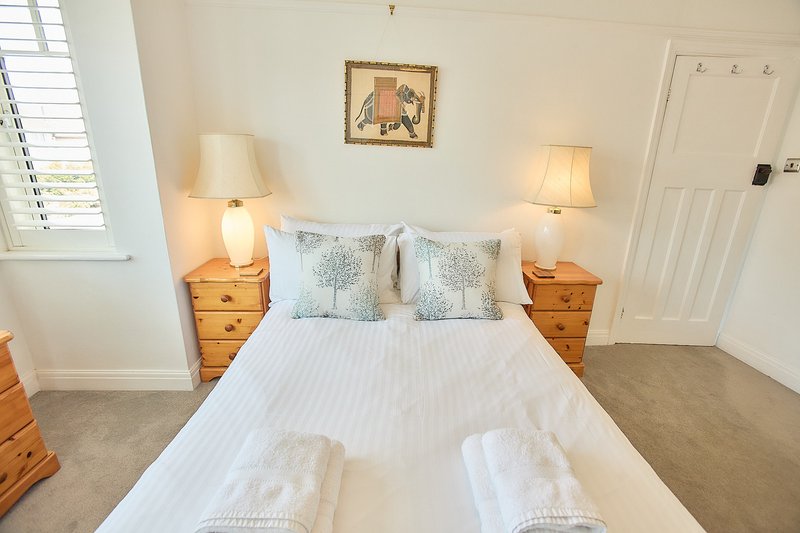 Bright bedroom with double bed, wooden nightstands, table lamps, and framed wall art