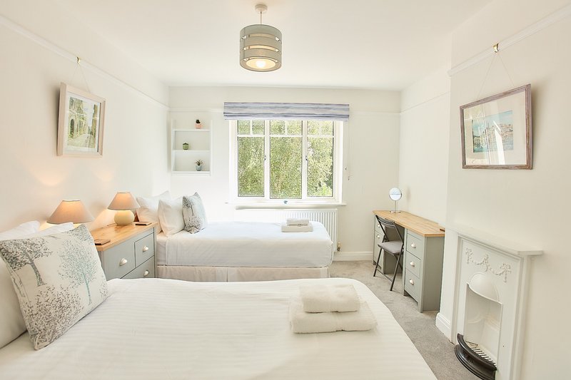 Bright bedroom with two single beds, white bedding, pendant light and garden views