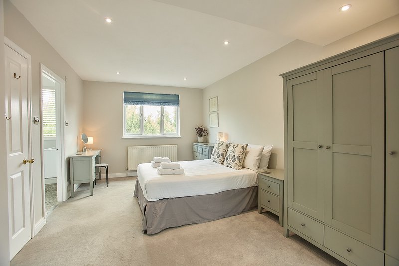 Spacious bedroom with double bed, green wardrobe, window seat and ensuite bathroom door