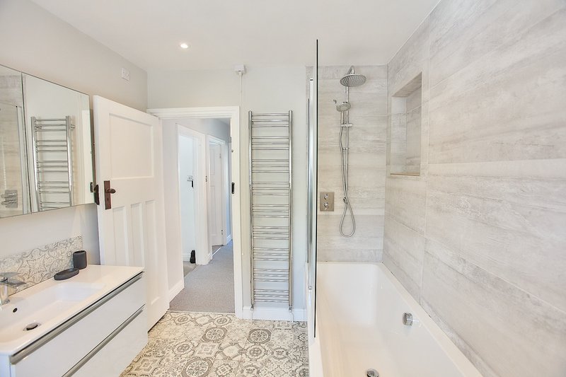 Modern bathroom with walk-in shower, double vanity sink, and patterned tile flooring