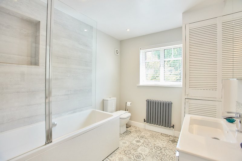 Bright bathroom with bathtub, shower enclosure, sink, radiator and window