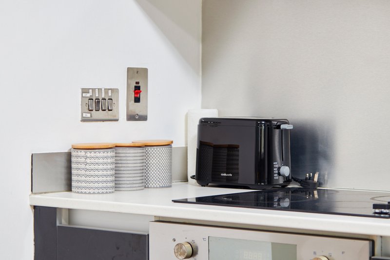 Kitchen counter with microwave, toaster, storage canisters and wall-mounted electrical outlets