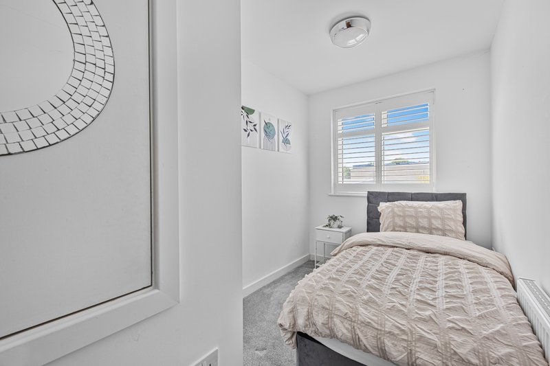 Modern bedroom with single bed, grey headboard, beige bedding and bright window