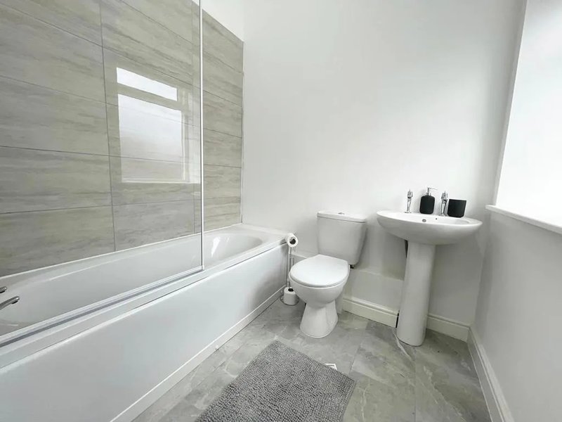 Modern bathroom with bathtub, shower enclosure, toilet, pedestal sink and grey floor tiles