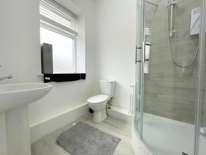 Modern bathroom with walk-in shower, toilet, sink, and window with natural light