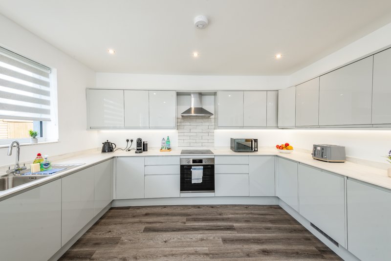 Modern white kitchen with built-in appliances, subway tile backsplash, and wood-effect flooring